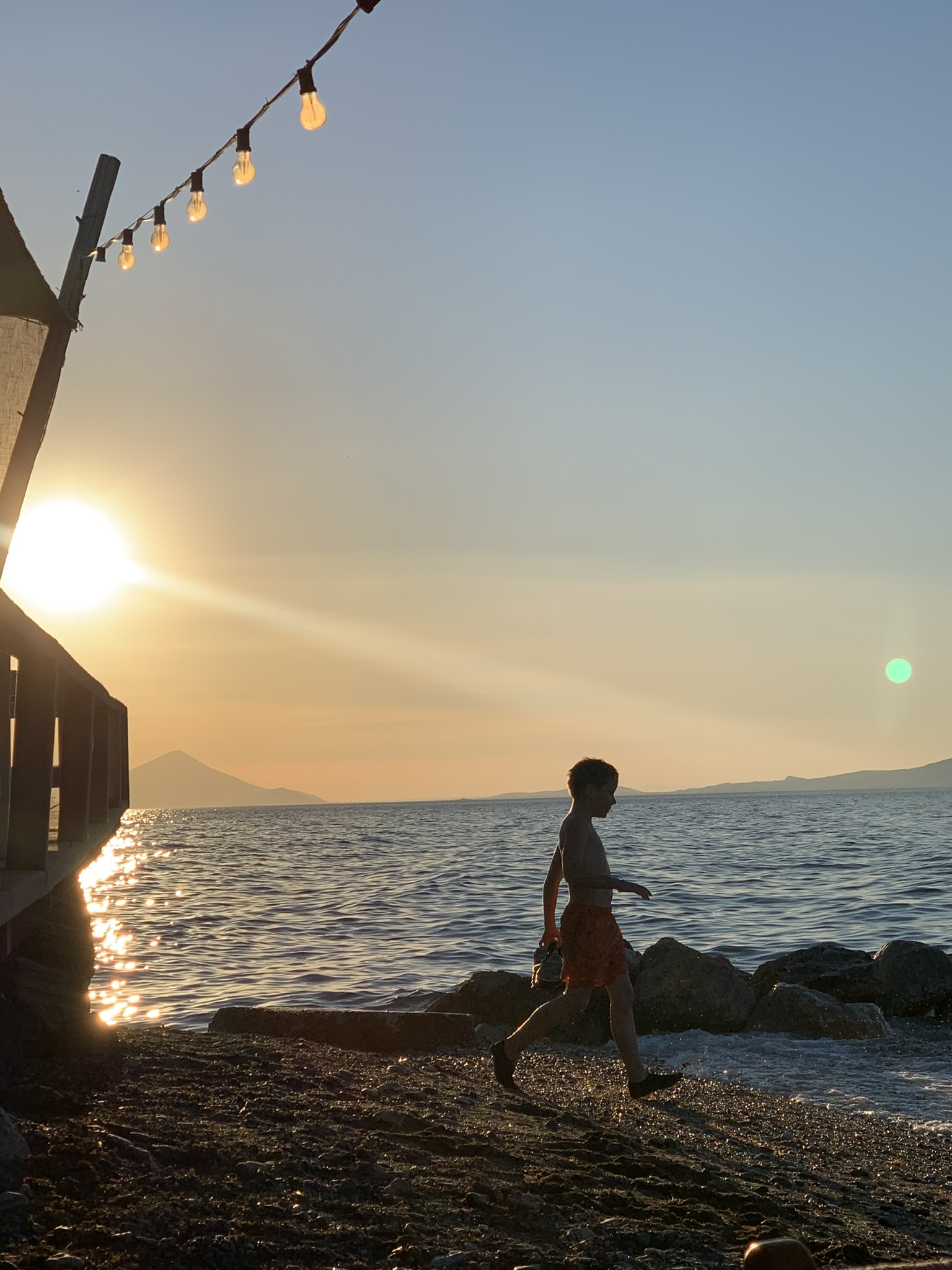 A boy walking past Alekos at sunset